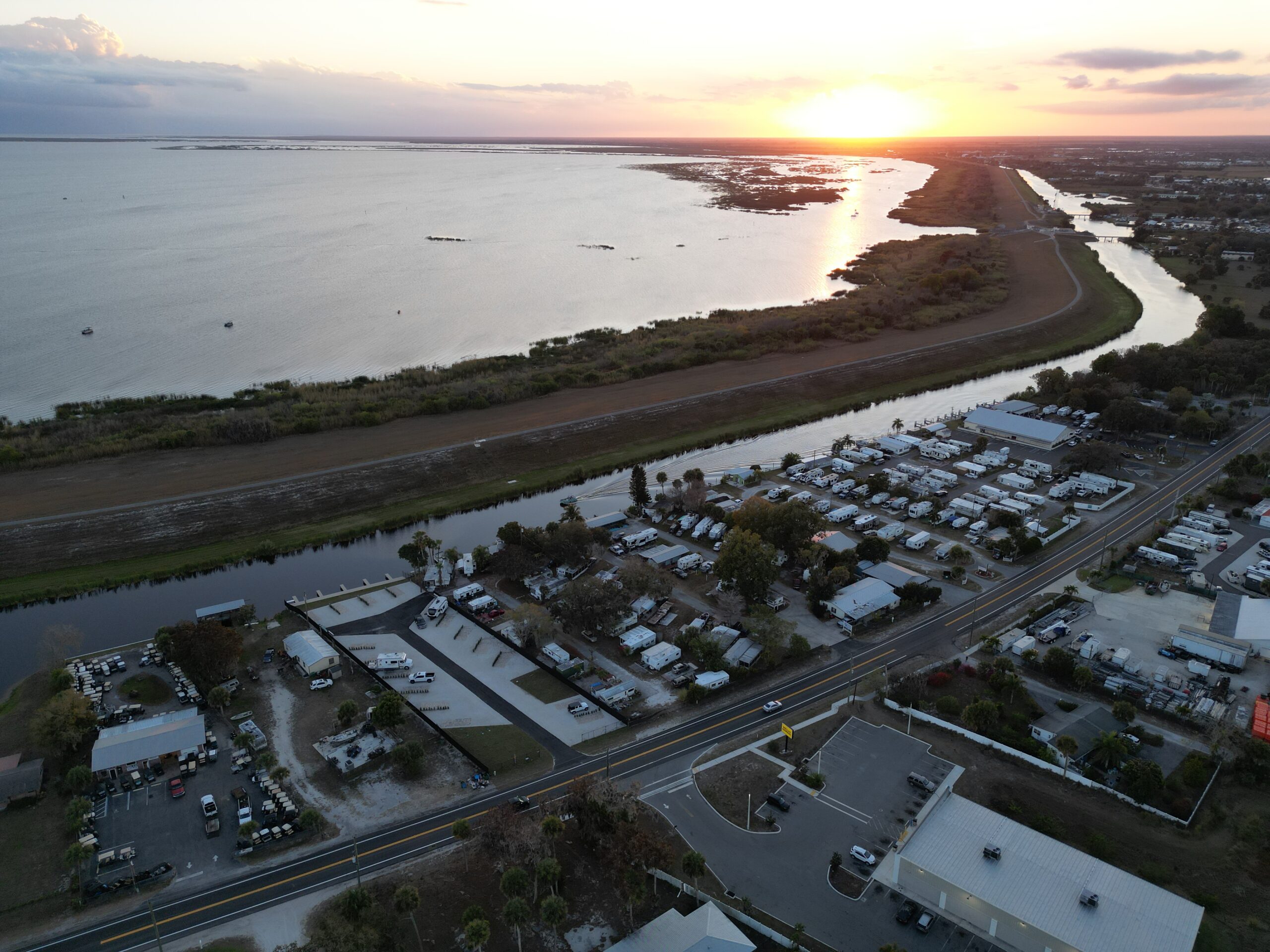 Waterfront RV sites at Buckin’ Bass RV Park in Okeechobee, Florida, seen from above at sunset.